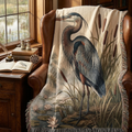 Great blue heron woven tapestry throw blanket draped over a leather armchair with vintage binoculars and field guide books nearby