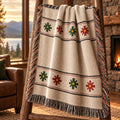 Ivory woven cotton throw blanket with a red, green, and gold Nordic star pattern and multicolor fringe draped over a wooden ladder rack by a window overlooking the lake