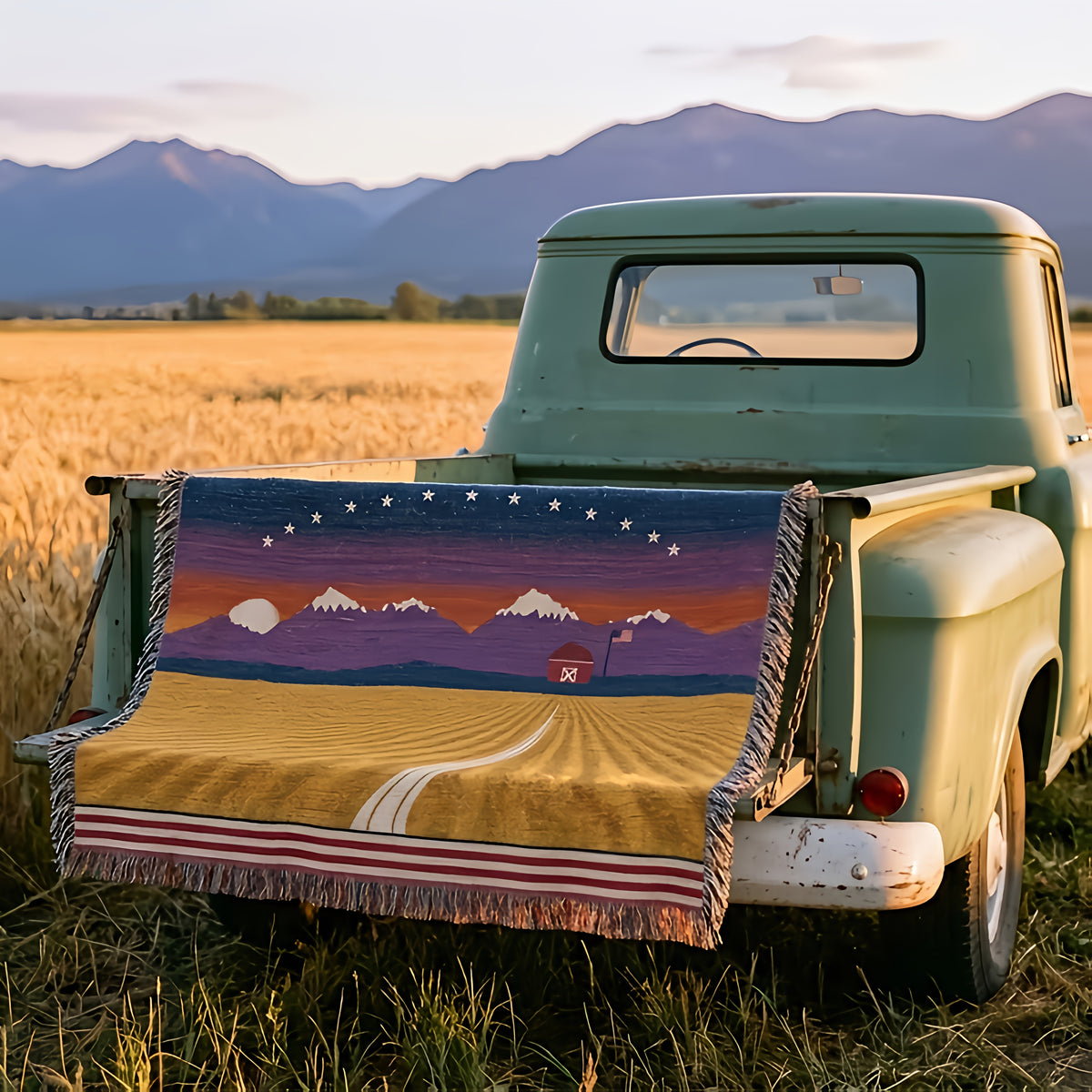 Amber Waves woven cotton throw over the tailgate of a vintage green pickup at the edge of a Montana wheat field