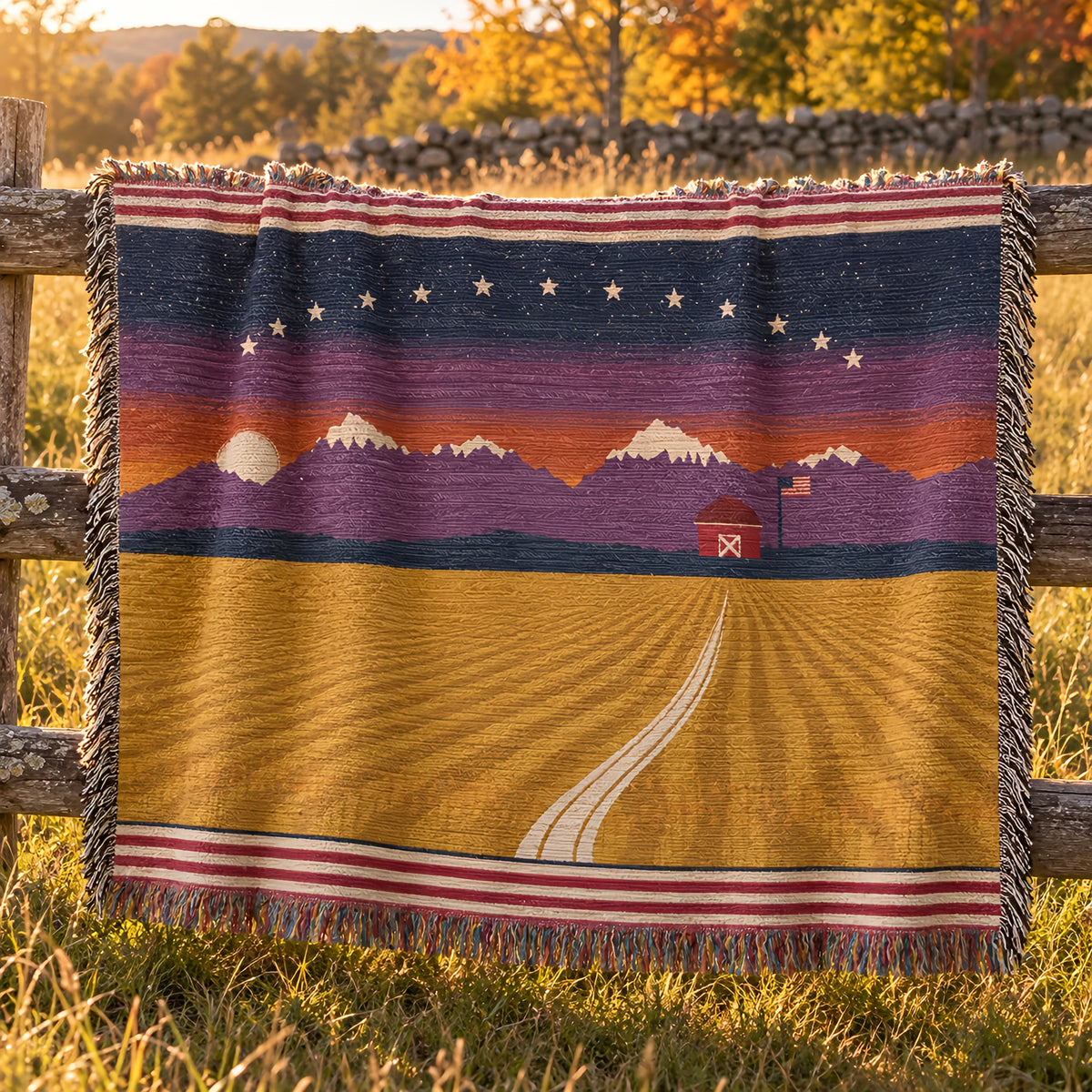 Amber Waves Americana woven throw over a split-rail fence by a fieldstone wall in golden autumn light
