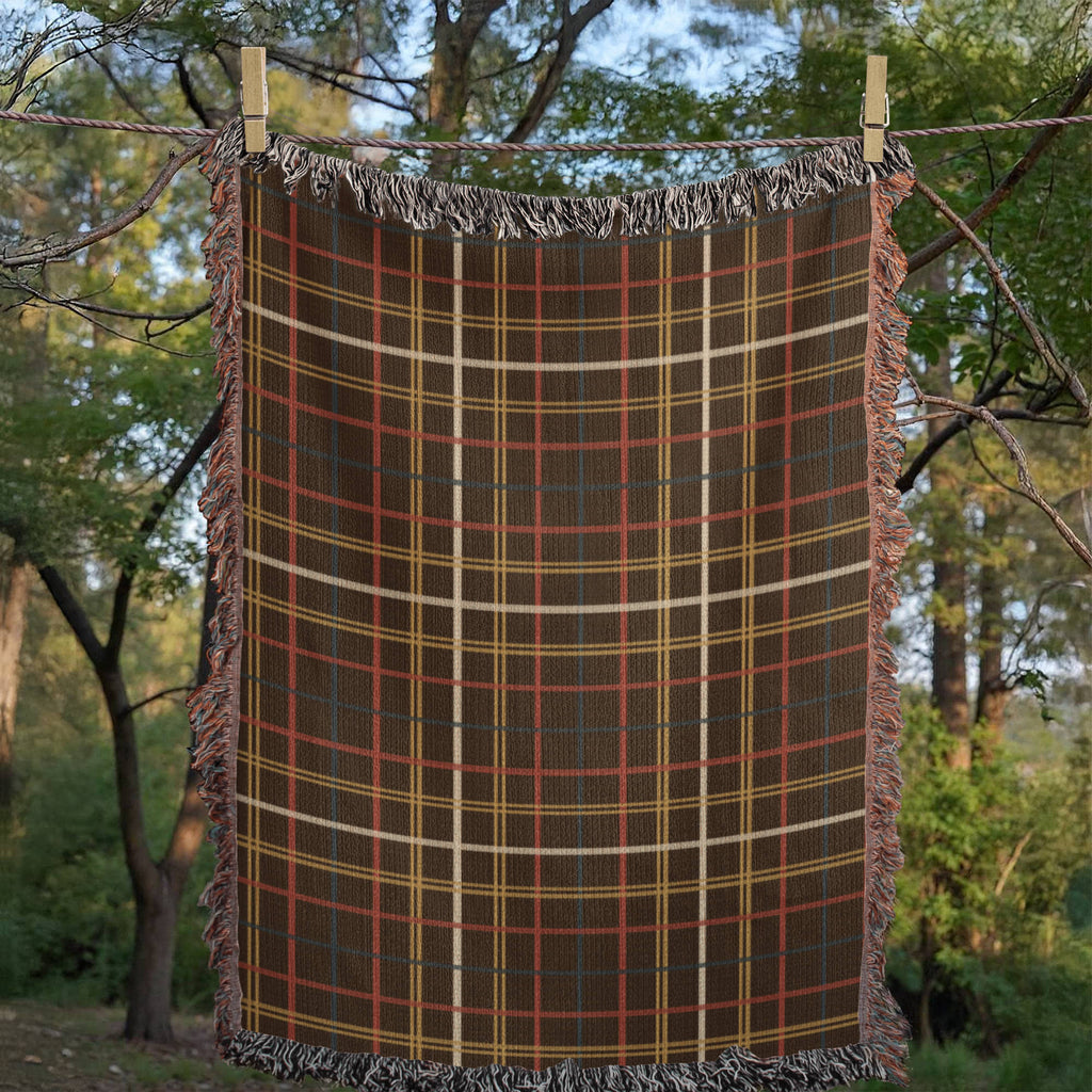 Woven mockup of the Espresso Heritage Sett design laid flat outdoors, showing the espresso brown tartan sett pattern with cream, doubled gold, and red-and-teal pinstripes crossing the warp and weft, before final rendering — Trini Skies
