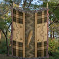 River Trout woven cotton throw blanket styled outdoors near the water, showing the jacquard woven texture and heritage stripe border in natural daylight — Trini Skies