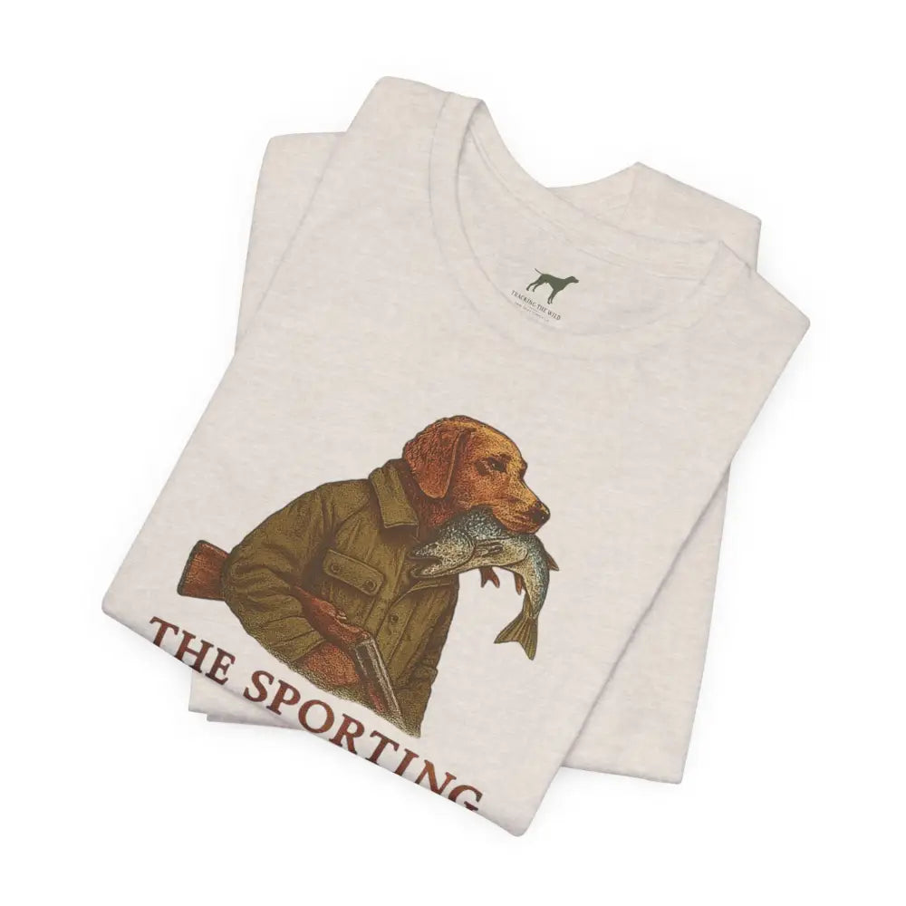 Folded white Trini Skies tee with dog in jacket holding fish, celebrate timeless outdoor heritage