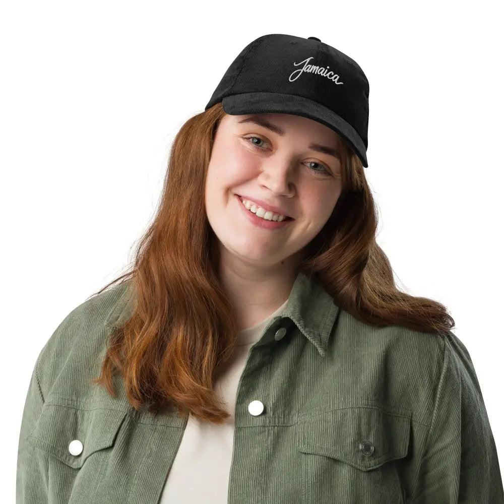 Smiling woman in Jamaica embroidered vintage corduroy cap and olive jacket
