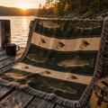 Trout and Fly woven tapestry throw blanket draped over rustic wooden bench at lakeside dock at golden hour showing brown trout, brook trout and fly fishing lure band detail — Trini Skies