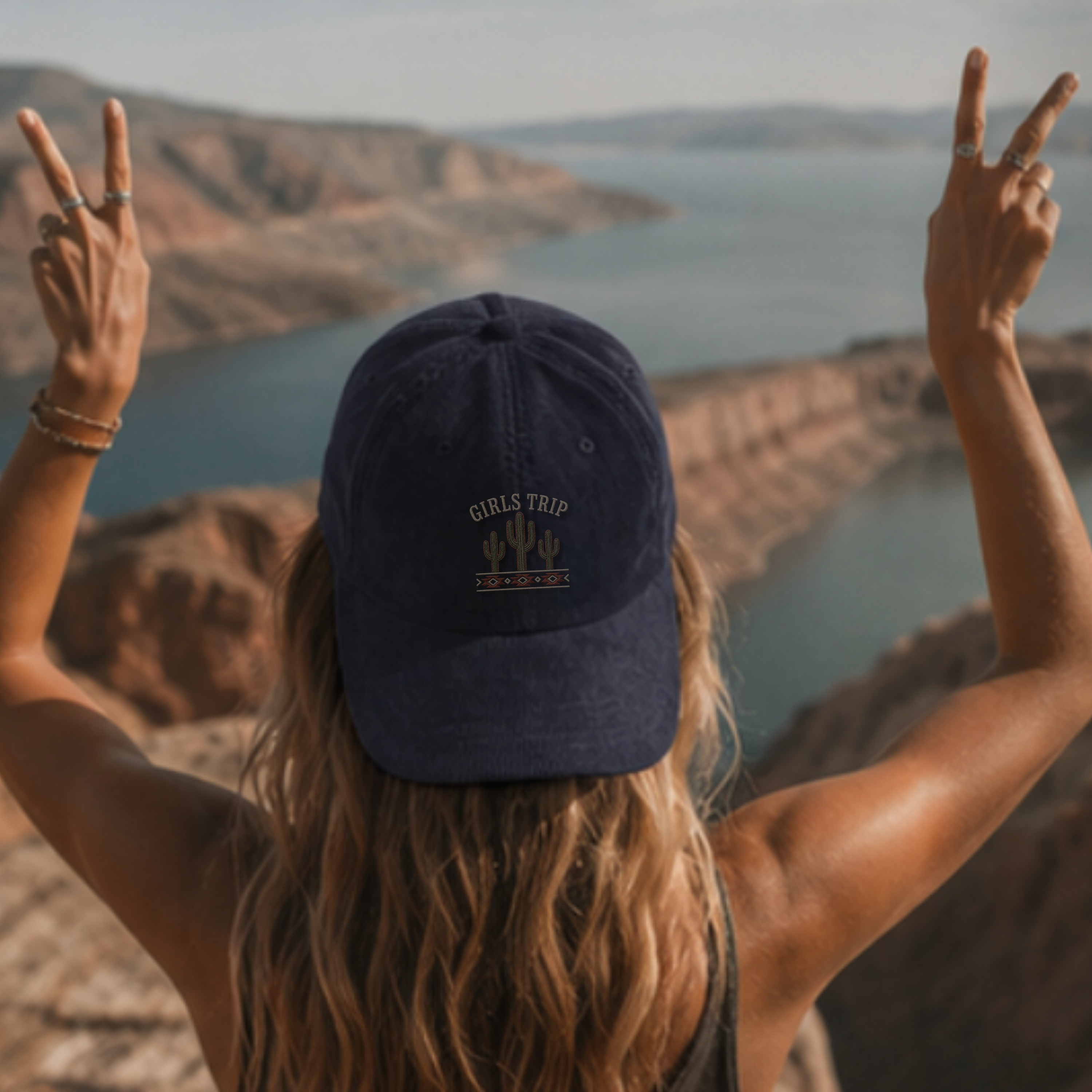 Person wearing Girls Trip cap at scenic lake and cliffs — Trini Skies outdoor hat