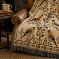 The Goldfinch Folk Sampler woven throw on a leather chair in a cabin — Trini Skies