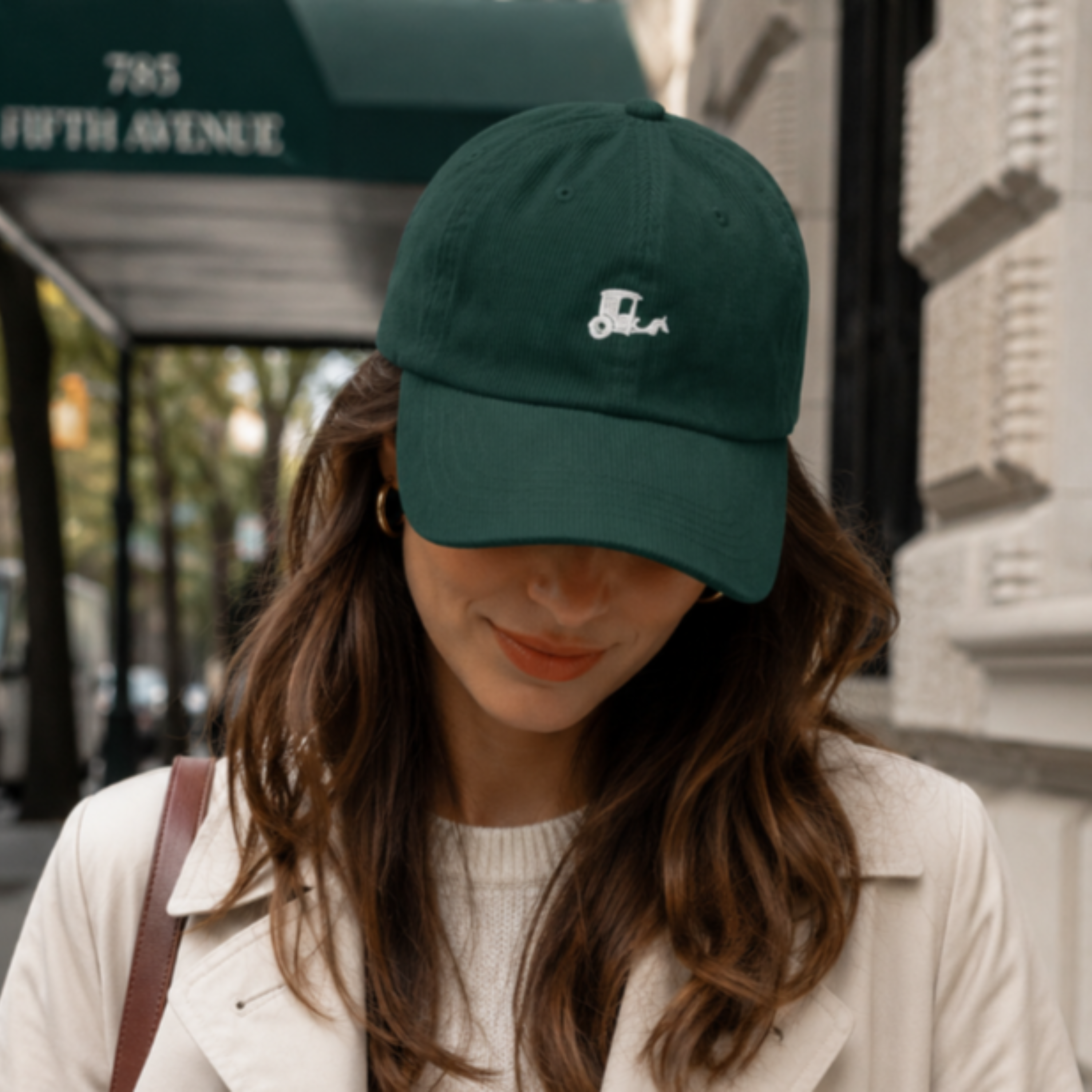 Woman walking New York City street wearing navy New York Carriage cotton twill dad hat camel coat autumn Trini Skies