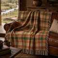 Teal and rust plaid woven cotton throw blanket draped over a leather sofa in a riverside cabin
