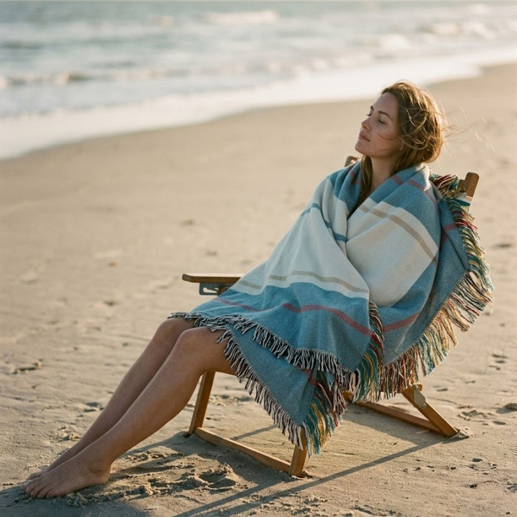 The Shorewood coastal blue heritage stripe woven cotton throw blanket shown full, faded blue and warm ivory design with barn red accent and signature multicolor fringe — Trini Skies