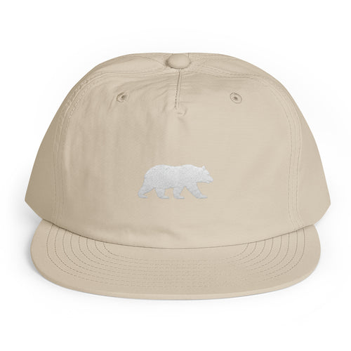 Ecru Big Sur Bear surf cap, front view, lightweight recycled-nylon travel hat with a small white embroidered walking bear emblem, Trini Skies