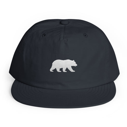 Navy Big Sur Bear surf cap, front view, lightweight recycled-nylon travel hat with a small white embroidered walking bear emblem, Trini Skies