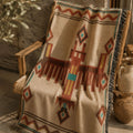 Thunderbird Southwestern woven cotton throw blanket draped over a wooden chair beside a potted olive tree — Trini Skies