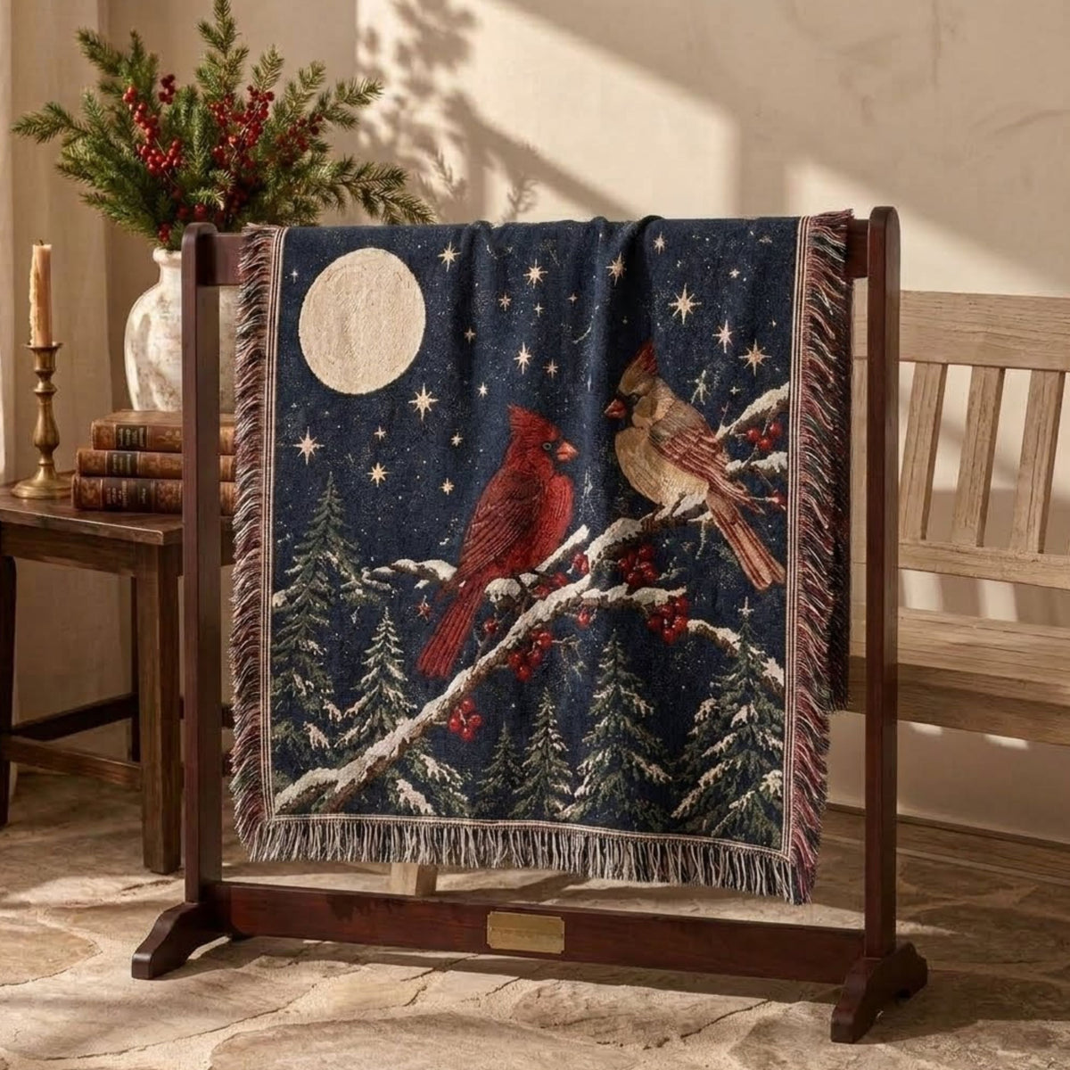 Navy cardinal pair woven throw blanket hung on a dark wooden quilt rack beside a bench with a winterberry arrangement