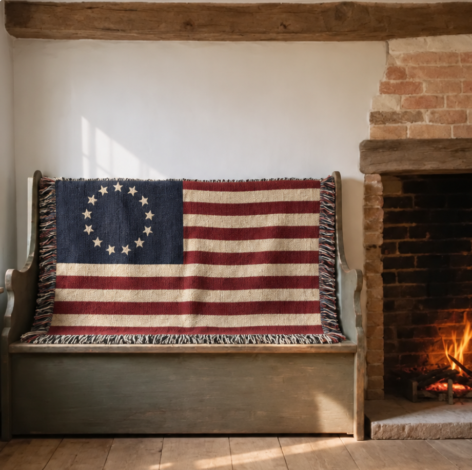 Betsy Ross flag woven throw on a painted colonial settle beside a brick hearth with a low fire