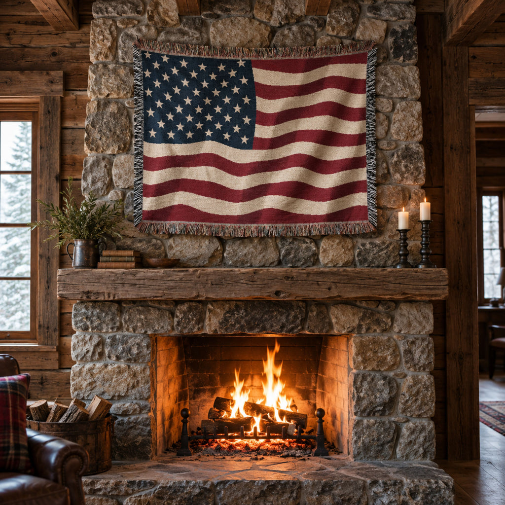 A rustic American flag tapestry hangs on a stone fireplace wall above a burning wood-burning stove. The scene includes a log cabin wall, stone masonry, a wooden mantel, and a warm fire in the hearth.