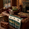 Hunter green Brook & Brown trout woven throw on a leather Chesterfield sofa by a lake lodge stone fireplace