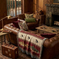 Lodge red trout and fly woven throw on a leather Chesterfield sofa in a lake lodge beside a stone fireplace