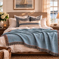 Chambray blue solid woven cotton throw blanket draped over a bed with a lake view