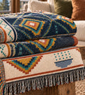 Rain Lattice navy geometric diamond woven cotton throw blanket folded on a table with a lake view